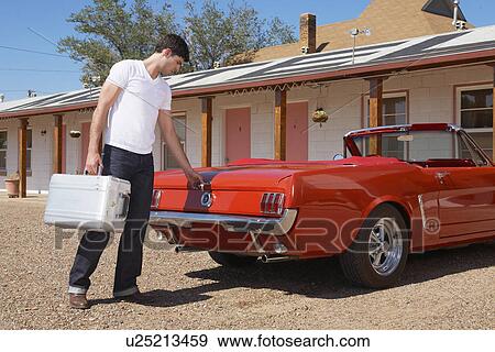 Stock Photo - Young man with briefcase locking car trunk. Fotosearch