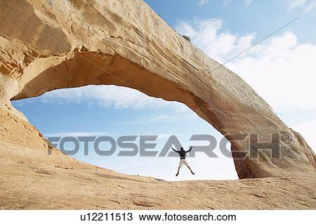Man jumping under red rock View Large Photo Image Stock Image - Man jumping under red rock. Fotosearch