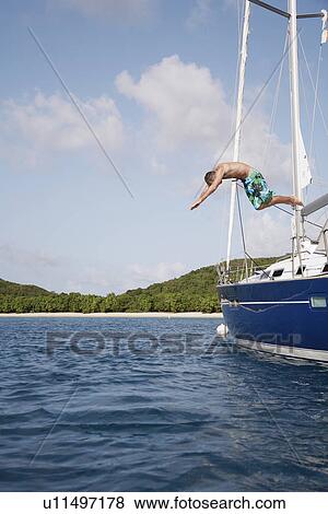 Mid adult man jumping from sailboat, St. John, US Virgin Islands, USA View Large Photo Image Stock Photo - Mid adult man jumping from sailboat, St. John, US Virgin Islands, USA. Fotosearch