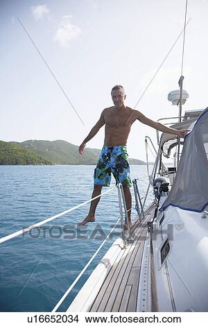 Mid adult man stepping over edge of sailboat, St. John, US Virgin Islands, USA View Large Photo Image Picture - Mid adult man stepping over edge of sailboat, St. John, US Virgin Islands, USA. Fotosearch