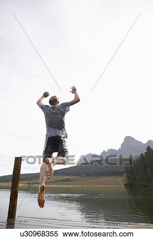 Stock Photography - Teenage boy jumping from jetty (rear view), Cape Town, South Africa. Fotosearch