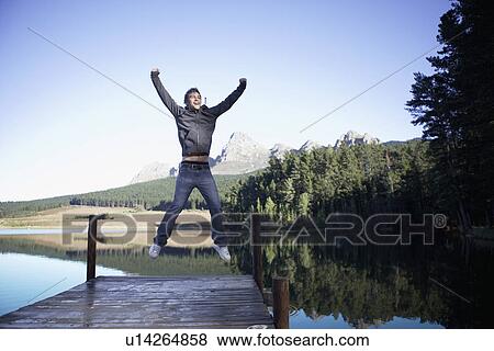 Stock Photo - Teenage boy jumping on jetty, Cape Town, South Africa. Fotosearch