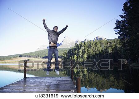 Stock Photo - Teenage boy jumping on jetty, Cape Town, South Africa. Fotosearch