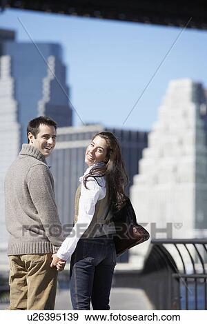 Couple holding hands and looking over shoulder (rear view), New York City, New York, USA View Large Photo Image Stock Photo - Couple holding hands and looking over shoulder (rear view), New York City, New York, USA. Fotosearch