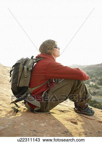 Stock Image - Male hiker sitting on rock. Fotosearch