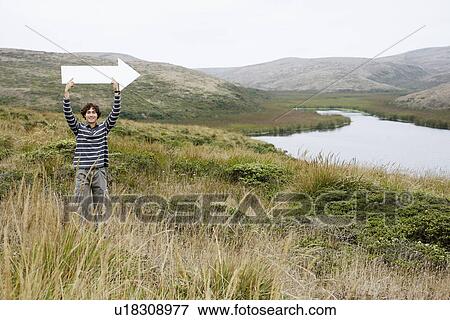 Man holding direction arrow in tall grass View Large Photo Image Stock Photo - Man holding direction arrow in tall grass. Fotosearch
