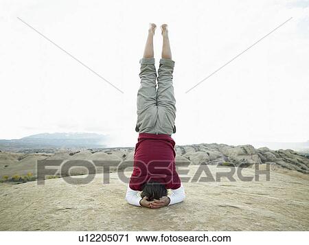 Stock Image - Man standing on head, rear view. Fotosearch