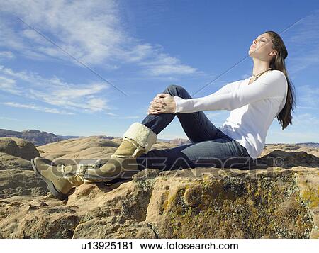 Young woman sitting on rock View Large Photo Image Stock Image - Young woman sitting on rock. Fotosearch