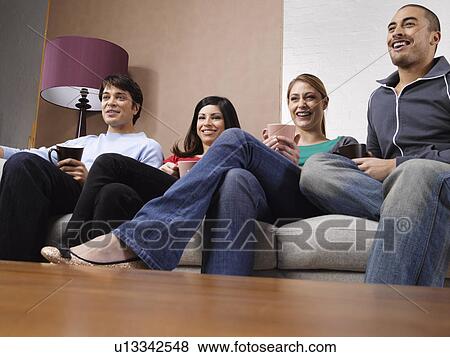 Four friends drinking coffee and watching TV on sofa View Large Photo Image Stock Photo - Four friends drinking coffee and watching TV on sofa. Fotosearch