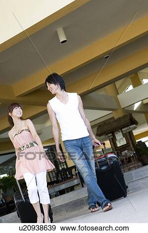 Stock Photo - Young couple carrying suitcases, smiling, Saipan, USA . Fotosearch