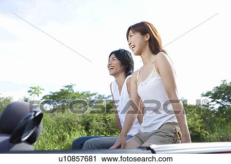 Stock Image - Young couple smiling and sitting on car seat, Saipan, USA. Fotosearch