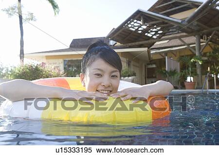 Stock Photography - Young woman in a swimming pool using inner tube, Saipan. Fotosearch