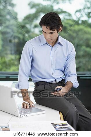 Stock Photography - Businessman with PDA using laptop. Fotosearch