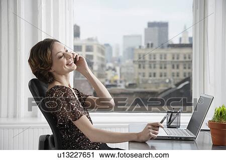 Businesswoman talking on the phone at desk View Large Photo Image Stock Image - Businesswoman talking on the phone at desk. Fotosearch