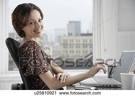 Stock Image - Female office worker at desk (portrait). Fotosearch