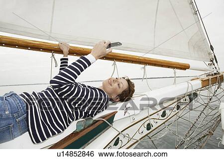 Mid adult woman lying on boat's bow and text messaging View Large Photo Image Stock Photograph - Mid adult woman lying on boat's bow and text messaging. Fotosearch