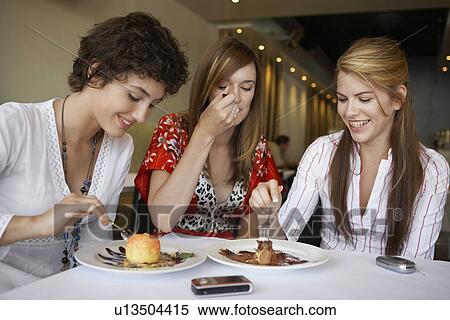 Stock Photography - Teenage girls eating deserts in restaurant. Fotosearch