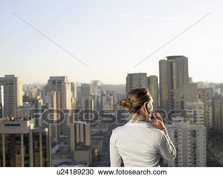 Businesswoman talking on cell phone, city in background (rear view), Sao Paolo, Brazil View Large Photo Image Stock Image - Businesswoman talking on cell phone, city in background (rear view), Sao Paolo, Brazil. Fotosearch