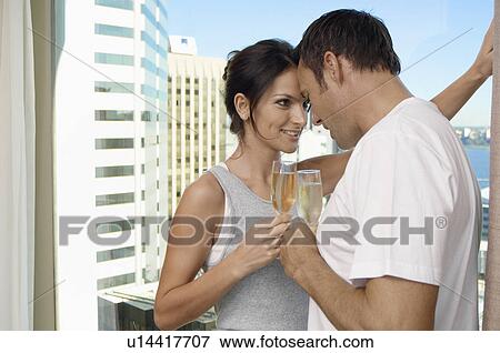 Stock Photo - Couple having champagne, skyscrapers in background. Fotosearch