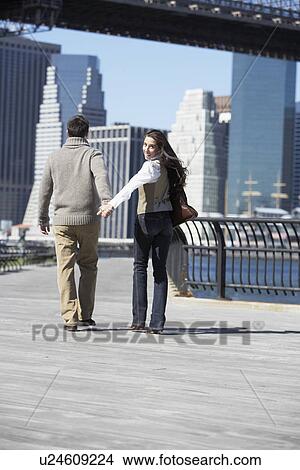 Picture - Couple walking on footbridge, woman looking back (rear view), New York City, New York, USA. Fotosearch