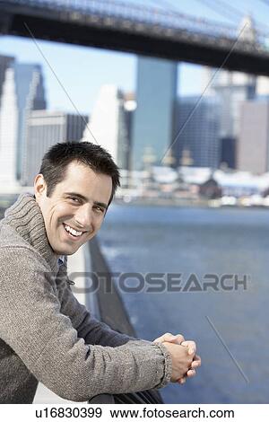 Stock Photo - Mid adult man leaning on railing (portrait), New York City, New York, USA. Fotosearch