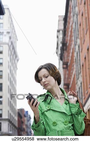 Mid adult woman using PDA on street, low angle view View Large Photo Image Stock Photo - Mid adult woman using PDA on street, low angle view. Fotosearch