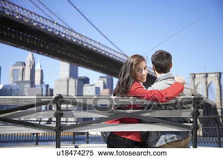 Young couple sitting near Brooklyn Bridge, woman looking over shoulder (rear view), New York City, New York, USA View Large Photo Image Stock Photography - Young couple sitting near Brooklyn Bridge, woman looking over shoulder (rear view), New York City, New York, USA. Fotosearch