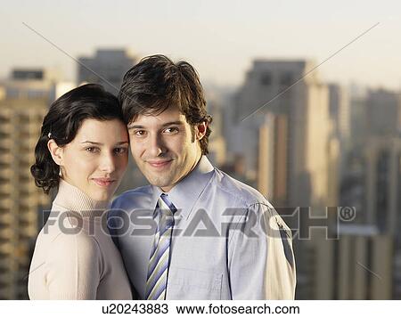 Stock Image - Young couple, skyscrapers in background (portrait). Fotosearch