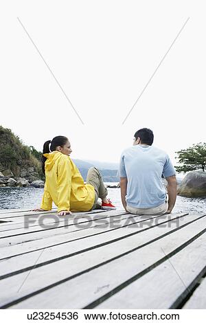 Young couple sitting on deck and talking View Large Photo Image Stock Photograph - Young couple sitting on deck and talking. Fotosearch