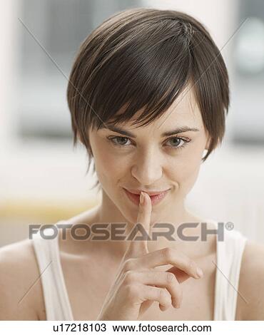 Stock Image - Young Woman with Finger on Mouth. Fotosearch