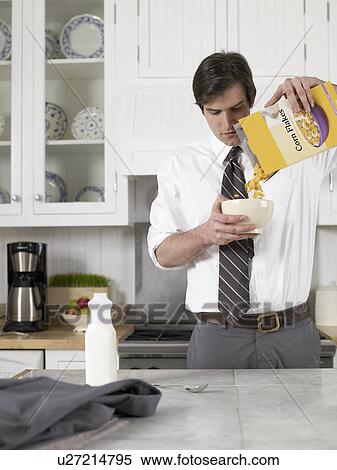 Stock Photography - Businessman pouring cereals in bowl. Fotosearch
