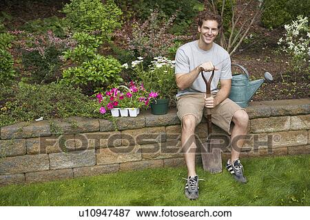 Male gardener sitting on brick wall (portrait) View Large Photo Image Stock Photo - Male gardener sitting on brick wall (portrait). Fotosearch