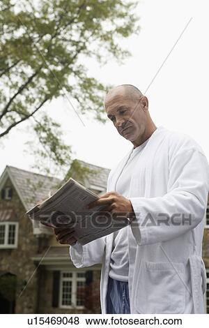 Stock Photo - Mature man in dressing gown reading newspaper outdoors, Chatham, New Jersey, USA. Fotosearch