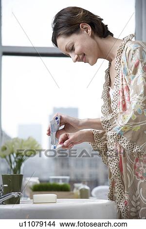 Mid adult woman squeezing toothpaste out of tube View Large Photo Image Picture - Mid adult woman squeezing toothpaste out of tube. Fotosearch