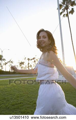 Stock Image - Young adult woman looking back and smiling, Side View, Low Angle View, Differential Focus. Fotosearch