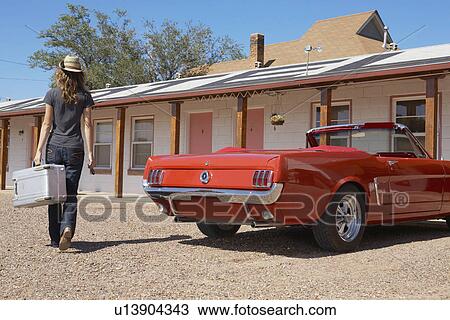 Stock Image - Young woman arriving at motel. Fotosearch