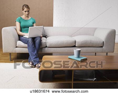 Young woman using laptop on sofa View Large Photo Image Picture - Young woman using laptop on sofa. Fotosearch