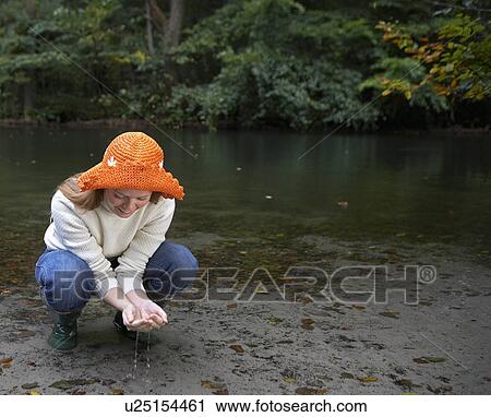 Stock Image - Woman Examining Water in Pond. Fotosearch