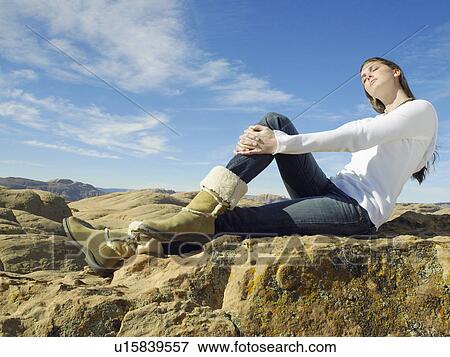 Stock Photo - Young woman sitting on rock. Fotosearch