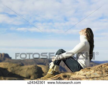 Young woman sitting on rocky hill View Large Photo Image Stock Image - Young woman sitting on rocky hill. Fotosearch