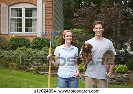 Young couple holding dog and garden tools View Large Photo Image Picture - Young couple holding dog and garden tools. Fotosearch
