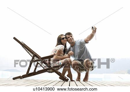 Stock Image - Young couple photographing themselves. Fotosearch
