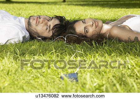 Young couple sharing MP3 player on grass View Large Photo Image Stock Image - Young couple sharing MP3 player on grass. Fotosearch