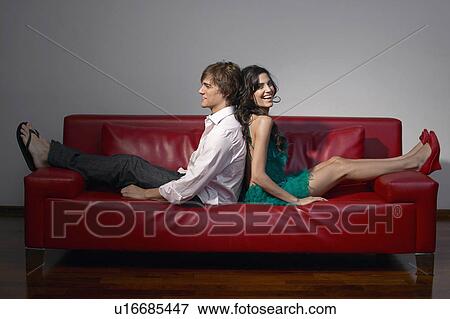 Stock Photo - Young Couple Sitting Back to Back on Leather Sofa. Fotosearch