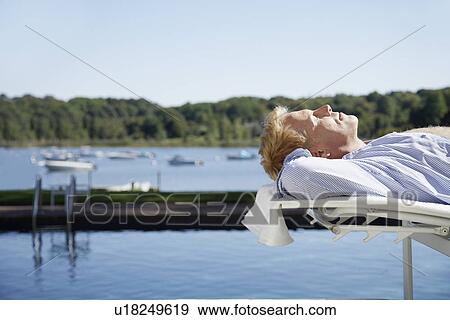 Man lying on lounge chair by swimming pool View Large Photo Image Stock Photo - Man lying on lounge chair by swimming pool. Fotosearch