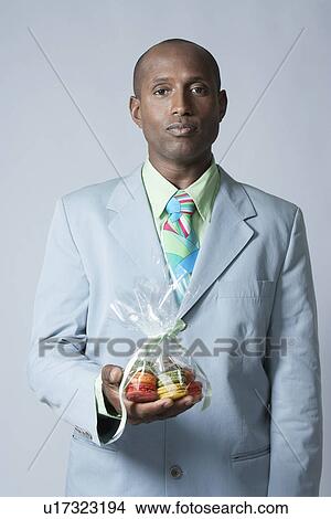 Picture - Mid adult man holding bag of biscuits. Fotosearch