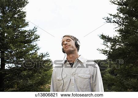 Mid adult man listening to headphones View Large Photo Image Stock Image - Mid adult man listening to headphones. Fotosearch