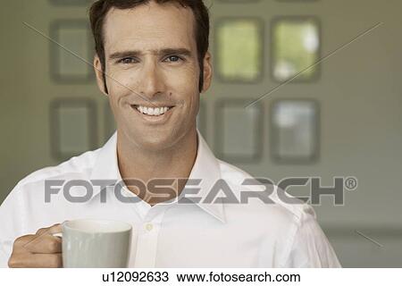 Stock Image - Mid adult man drinking coffee. Fotosearch