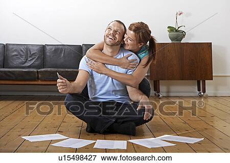 Stock Photo - Mid Adult Man Doing Paperwork, Girlfriend Hugging Behind. Fotosearch