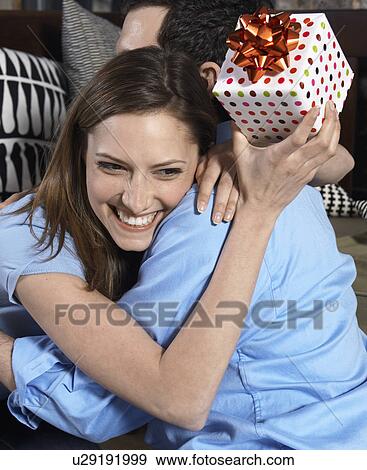 Stock Photo - Mid-Adult Woman with Present Hugging Boyfriend. Fotosearch